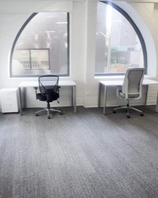 Two desks beneath tall arched windows in the Clarkes.Team office