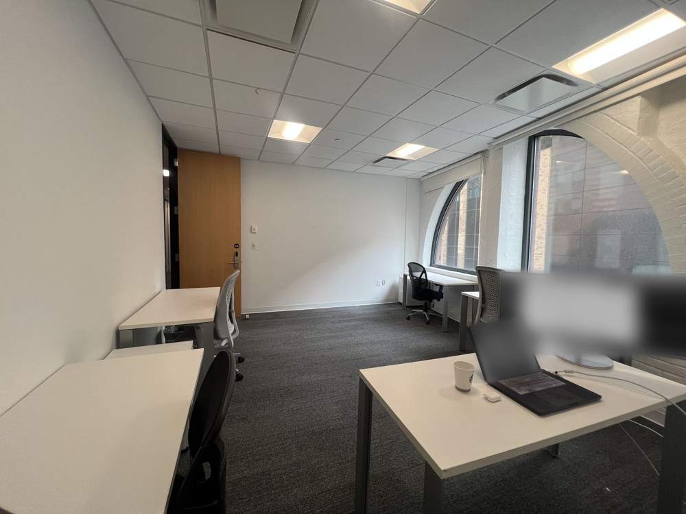 The Clarkes.Team office interior, with desks along an exposed brick wall